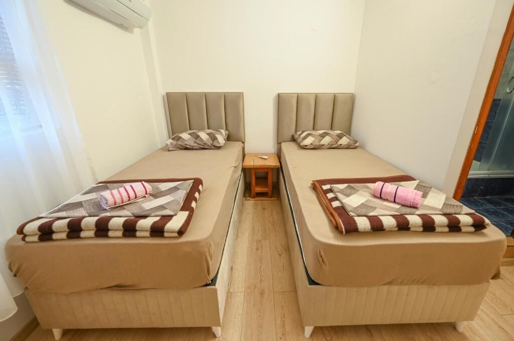 A twin bedroom with two single beds, each with a pillow and a striped blanket.