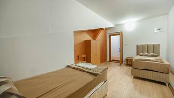 Ein kleines, helles Schlafzimmer mit zwei Betten, einem Kleiderschrank und einer Tür zu einem anderen Raum.
