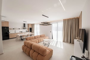 Un soggiorno moderno con un divano componibile, un'area pranzo e una cucina sullo sfondo.