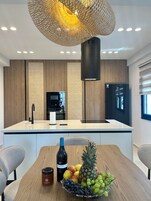 Una cucina moderna con isola centrale, mobili in legno, forno a incasso e frigorifero nero.