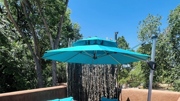 An outdoor patio area with wicker furniture and a blue umbrella. - Art-Filled South Capitol Retreat \ Walkable \ Private Patios & Deck \ AC (Santa Fe)
