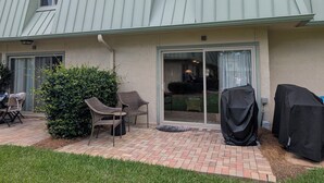 A building with a patio area, outdoor seating, and covered barbecue equipment. - Beach/Pool Access-Location Location Location! (Hilton Head Island)