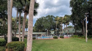 A pool area with lounge chairs, surrounded by palm trees and a fence. - Beach/Pool Access-Location Location Location! (Hilton Head Island)