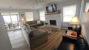 A living room with a sofa, coffee table, fireplace, and a TV. - Saltaire Cottages15: Just Renovated! 3BR Private Beach Access Ocean View Pool! (Kitty Hawk)