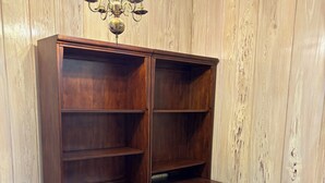 Un escritorio de madera con estantes y cajones abiertos, una silla y una araña.