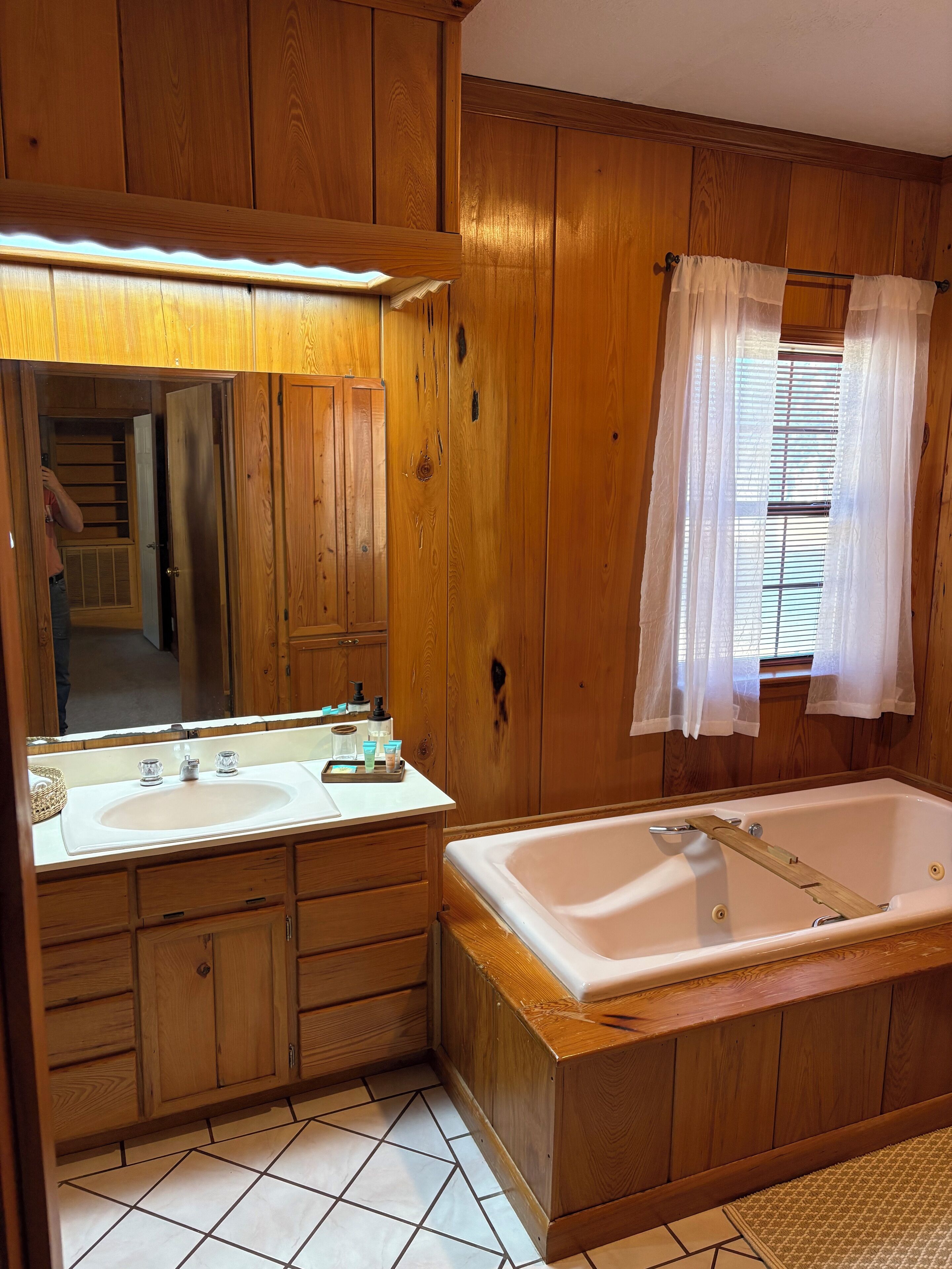 Un bagno in legno con due lavabi, una vasca da bagno ampia e uno specchio sopra il lavabo.