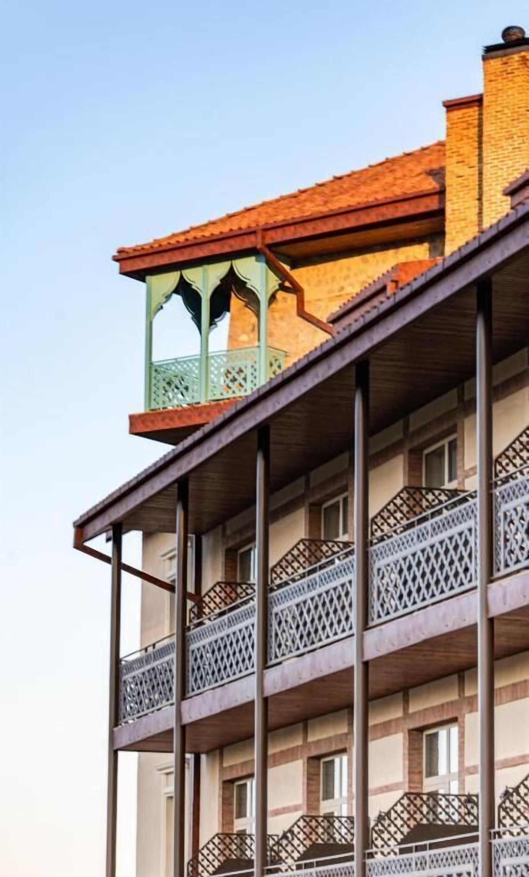Un edificio de varios pisos con balcones, techo de madera y fachada de ladrillo.