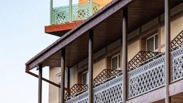 Un edificio de varios pisos con balcones, techo de madera y fachada de ladrillo.