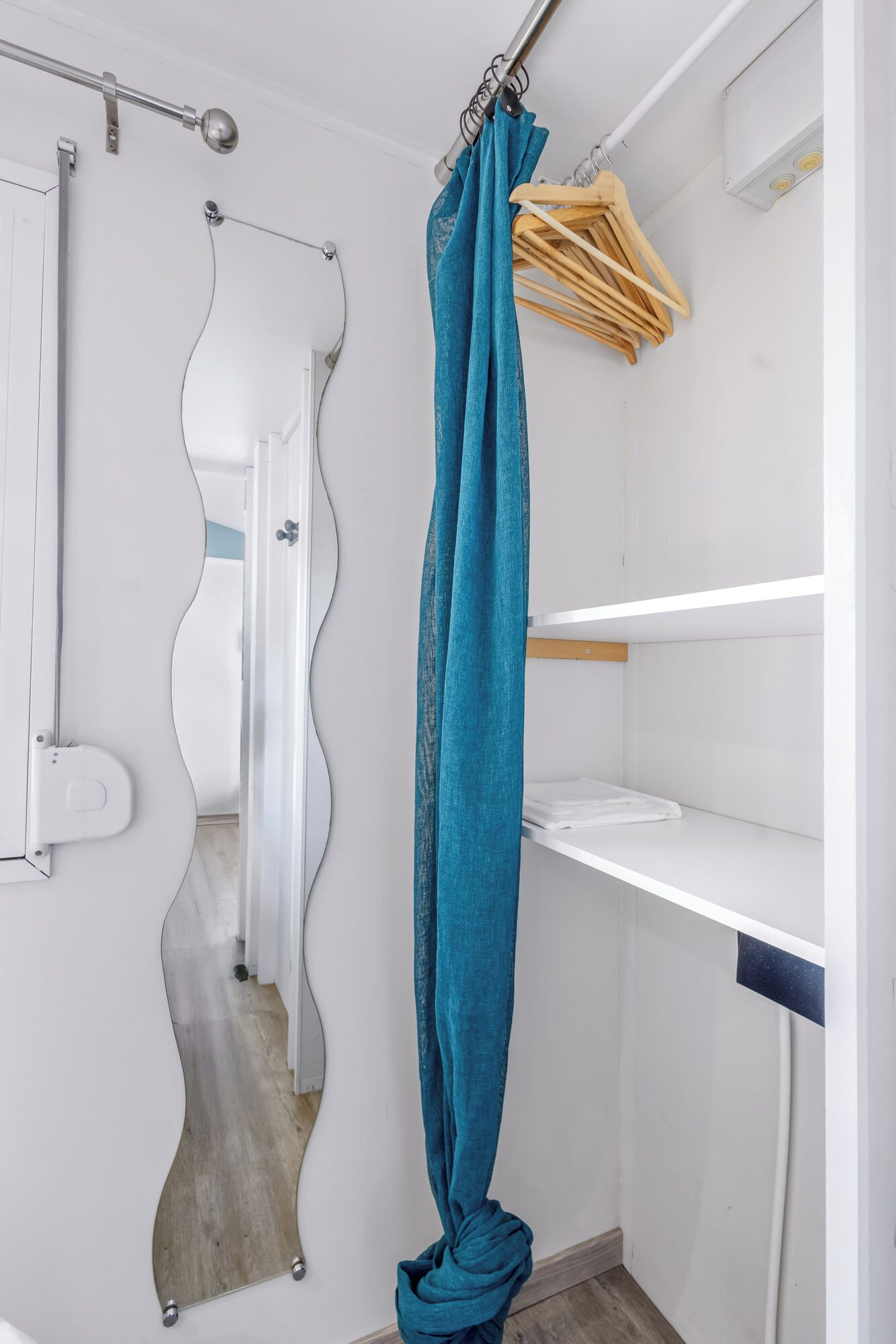 Une salle de bain avec un rideau de douche, un miroir et un porte-manteau en bois.