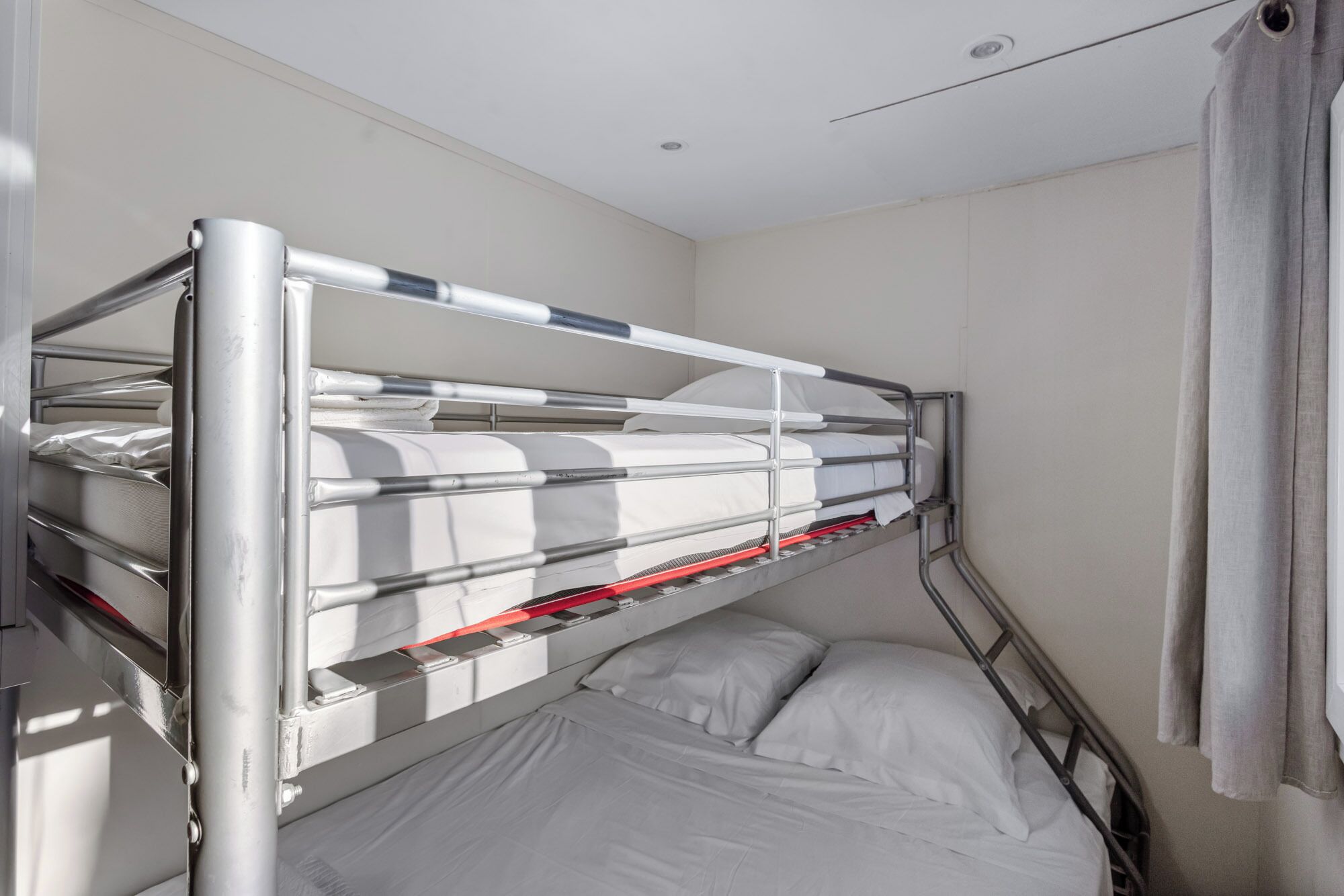 Een stapelbed met metalen spijlen en een enkel bed eronder.