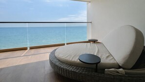 Uma varanda com sofá de vime e uma pequena mesa, com vista para o mar.