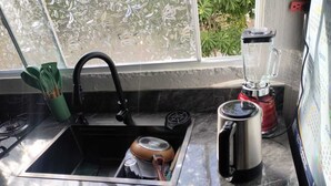 Une cuisine équipée d’un évier, d’une bouilloire et d’un mixeur sur le plan de travail.