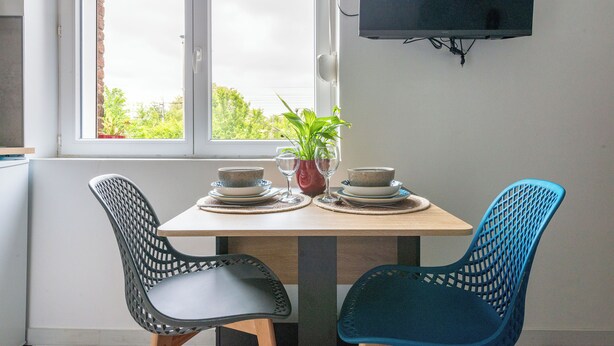A dining table set with plates, glasses, and a potted plant. Two chairs are positioned on either side of the table. - Charming, light-filled studio - Centre-ville-Gare (Cambrai)