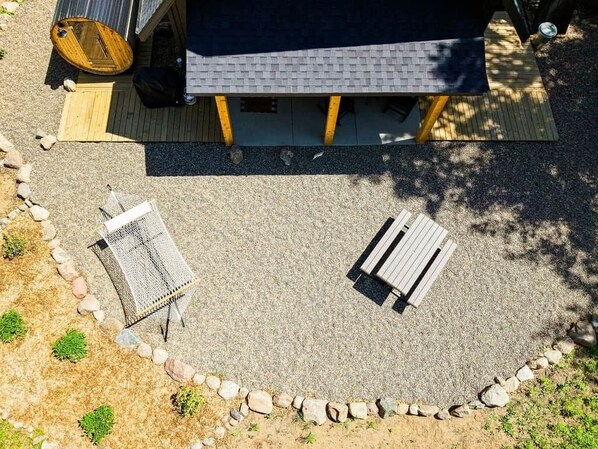 Un patio con dos espacios de descanso, una terraza de madera y un edificio con techo oscuro.