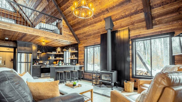 A spacious living area with a high ceiling, a fireplace, and a kitchen with modern appliances.