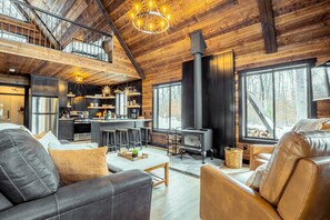 A spacious living area with a high ceiling, a fireplace, and a kitchen with modern appliances.