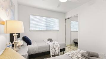 Quarto com cama, mesa de cabeceira, abajur e um espelho grande.