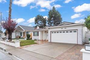 A single-story house with a garage, a front yard with a tree, and a clear sky. - 3BR Home Ideal for Work Trips, Family & Long Stays (Fremont)