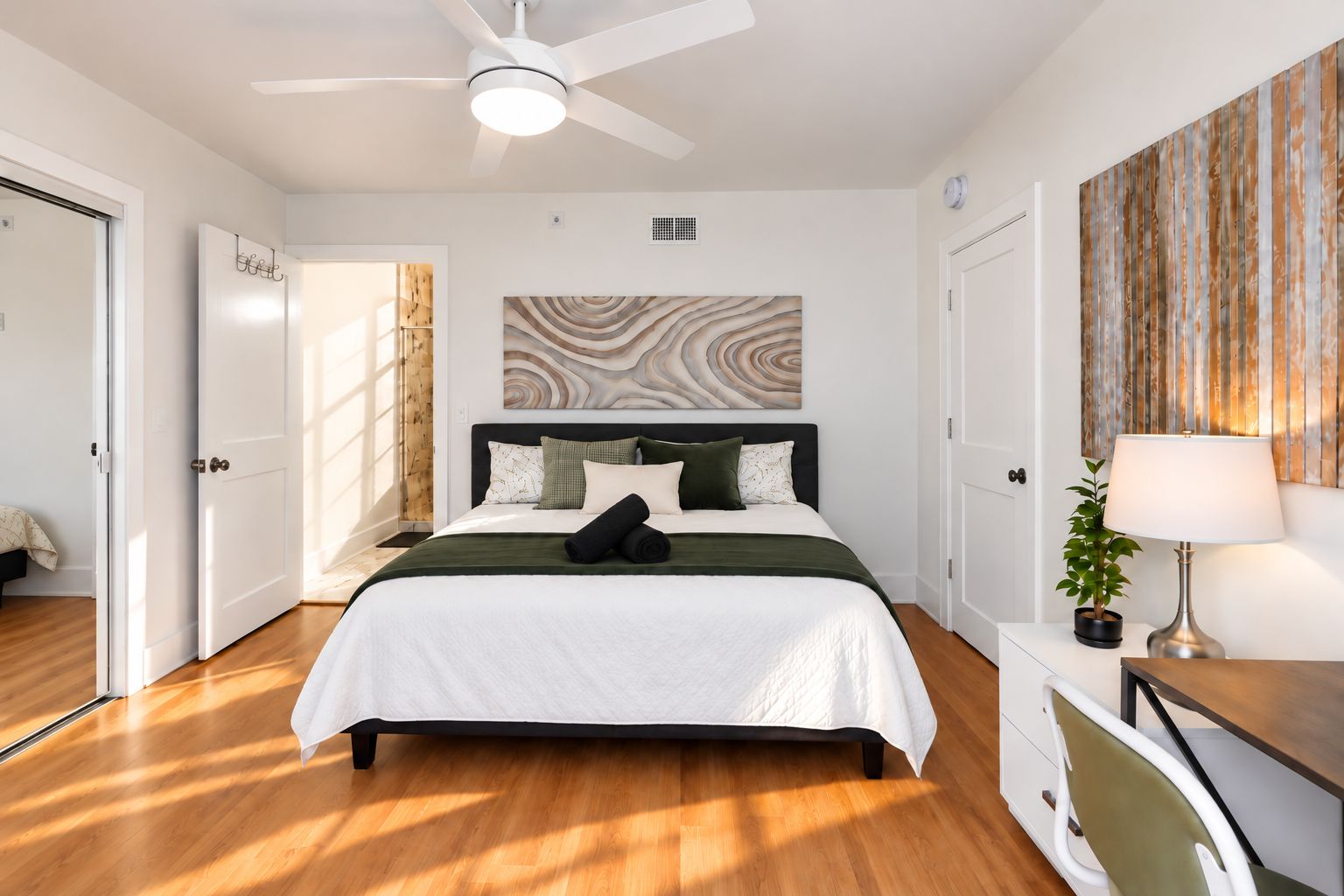 Bright, stylish bedroom with workspace, hardwood floors, and natural light