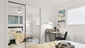 Ein modernes Schlafzimmer mit Bett, Nachttisch, Lampe und Schreibtisch mit Stuhl.