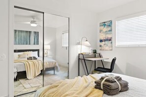 A modern bedroom with a bed, bedside table, lamp, and a desk with a chair. - 3BR Home Ideal for Work Trips, Family & Long Stays (Fremont)