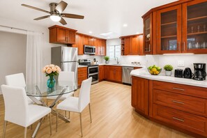 A modern kitchen with wooden cabinets, stainless steel appliances, and a glass dining table. - 3BR Home Ideal for Work Trips, Family & Long Stays (Fremont)