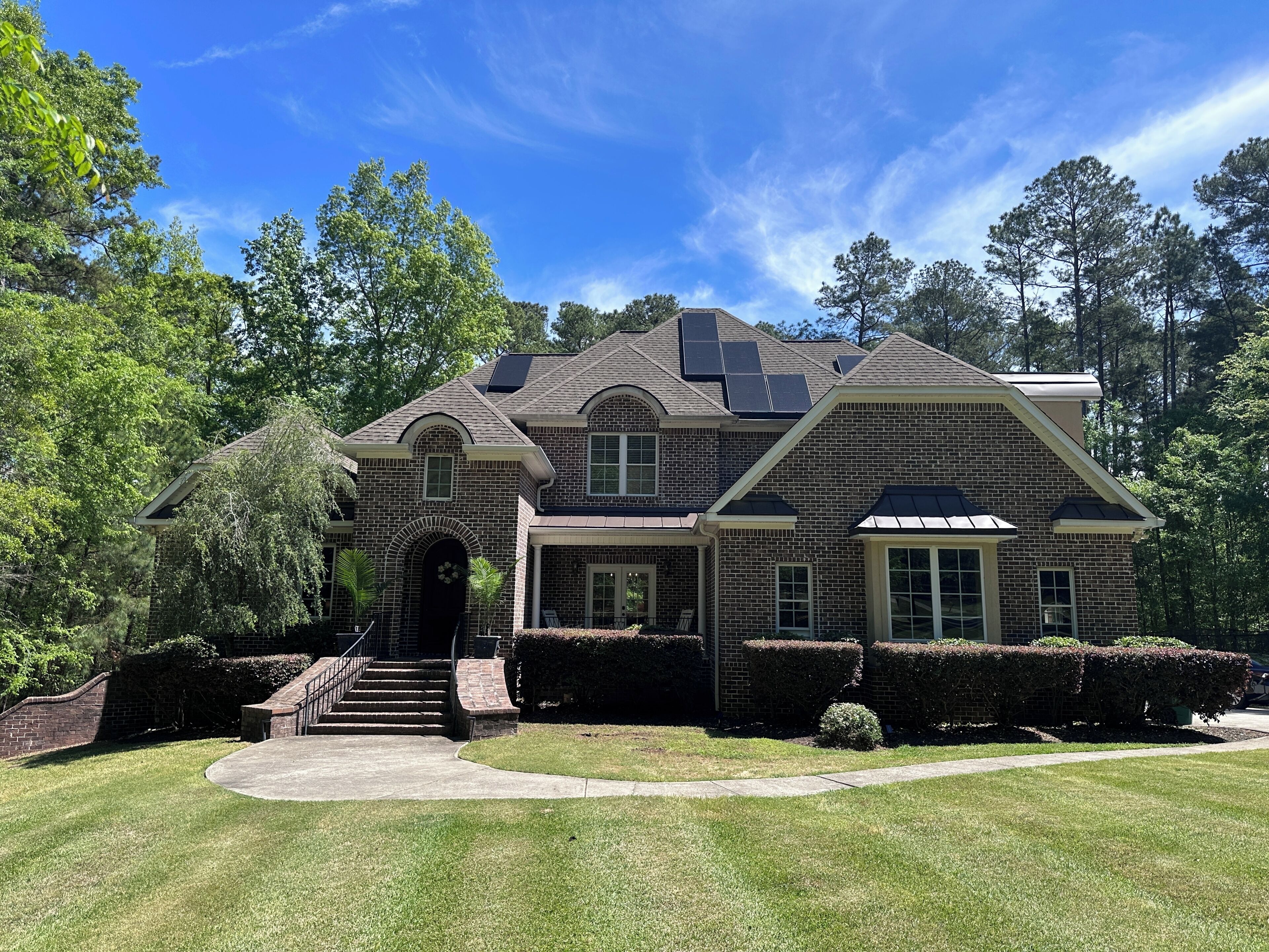 A two-story house with a brick facade, a front entrance with steps, and a driveway.