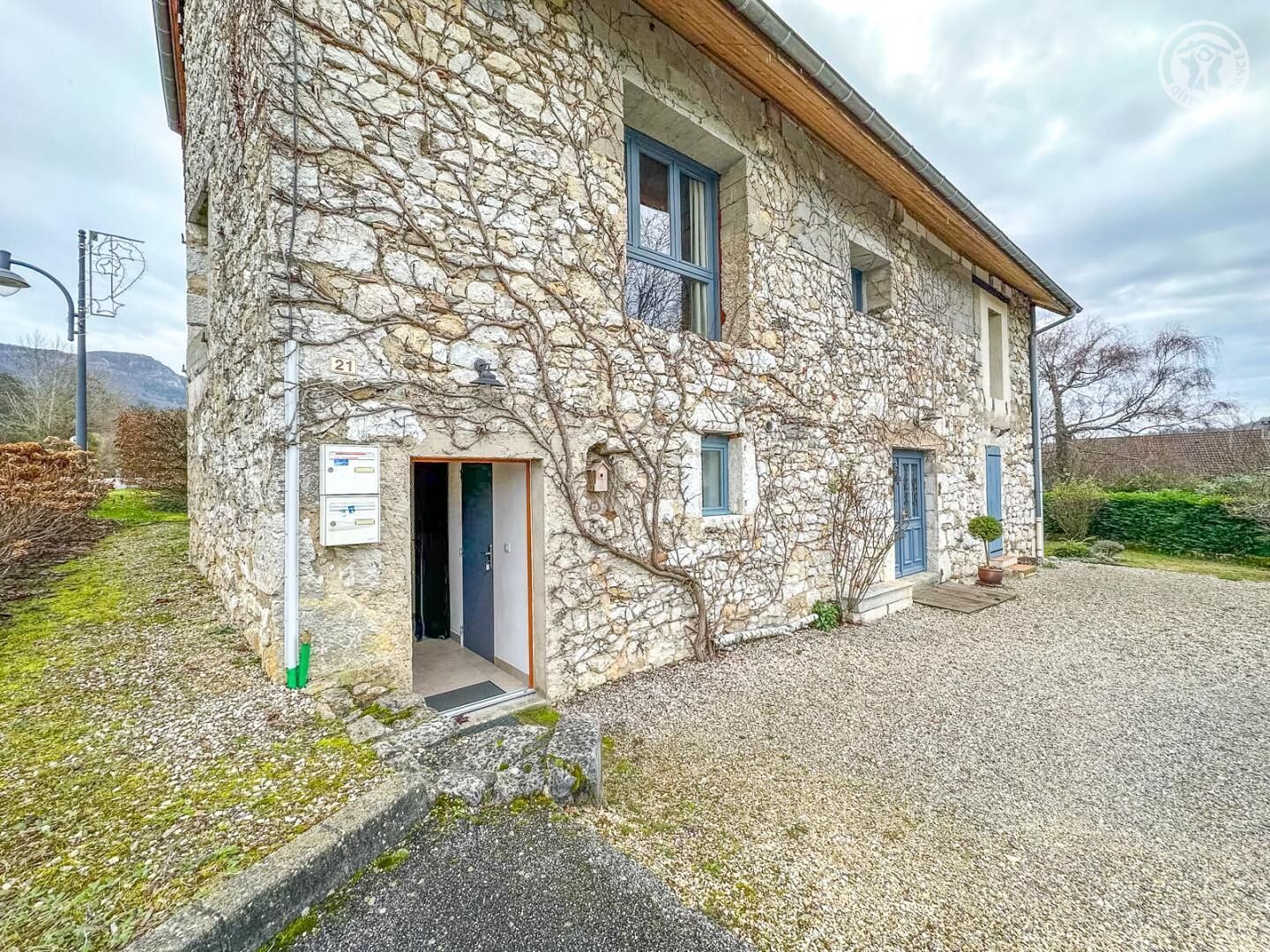 Ein Steinhaus mit Schotterauffahrt und einer kleinen Eingangstür.