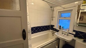 A bathroom with a bathtub, a sink, and a window.
