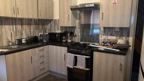 A modern kitchen with wooden cabinets, a gas stove, a coffee maker, and a microwave.