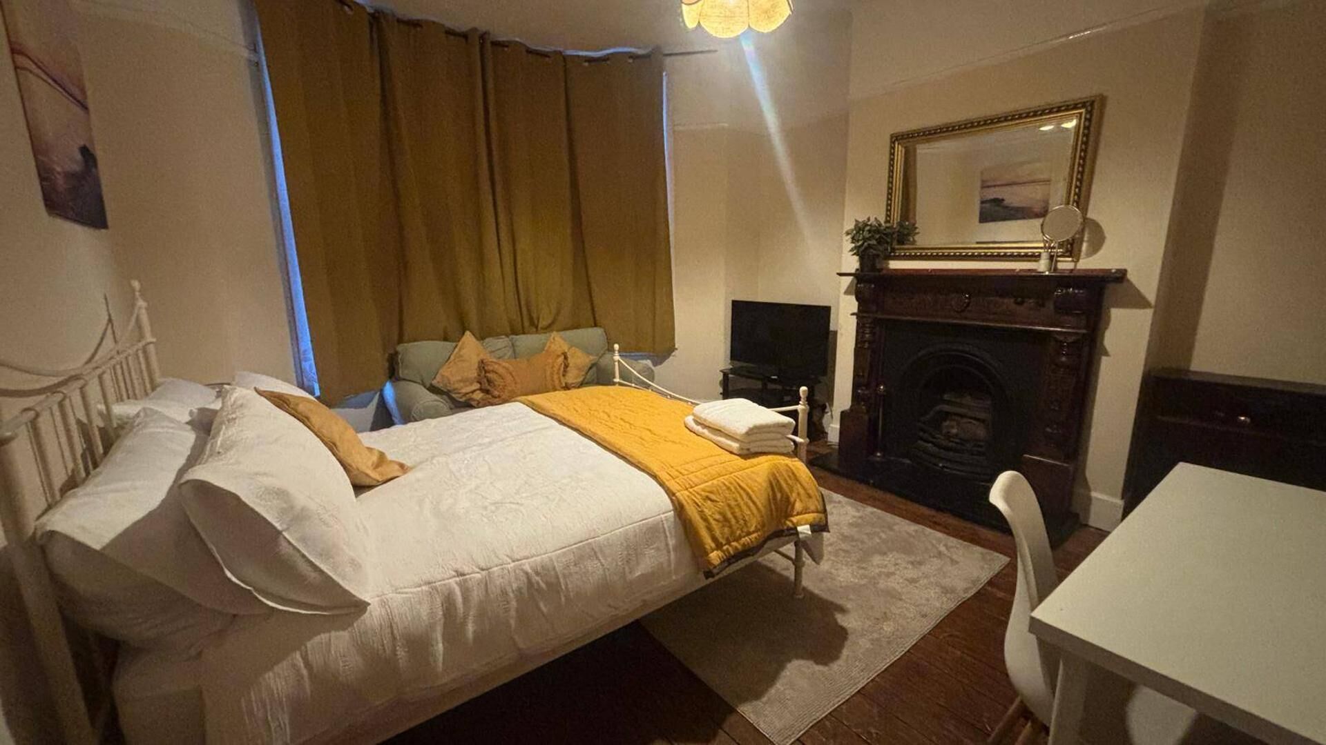 Ein Schlafzimmer mit einem Bett, einem Fernseher, einem Kamin und einem Spiegel.