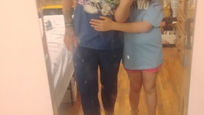 Un espejo refleja a una persona con camiseta azul con un personaje de caricatura y texto, de pie junto a un niño con camisa azul.