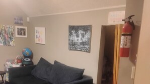 Una sala de estar con un sofá verde oscuro, un globo terráqueo y un extintor en la pared.