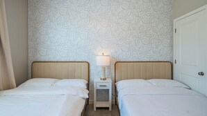 A double room with two beds, a nightstand with a lamp, and a patterned wallpaper. - The One 216 (Glendale)