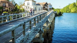 Un pont de pierre enjambe une rivière, avec des bâtiments de chaque côté.