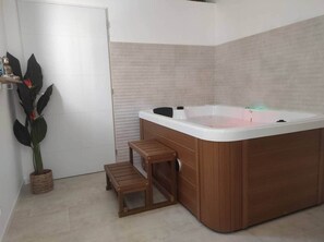 A modern bathroom with a wooden bathtub, a small wooden stool, and a potted plant. - Villa Spa Béziers 4* (Béziers)