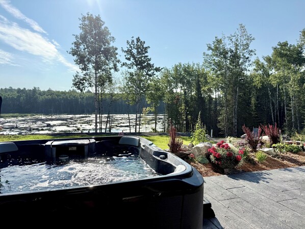 A hot tub with a view of a forest and a body of water.