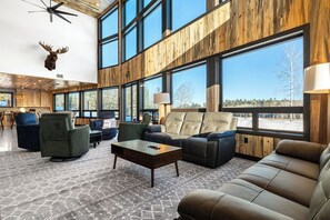 A spacious lobby with large windows, a ceiling fan, and a mounted deer head.