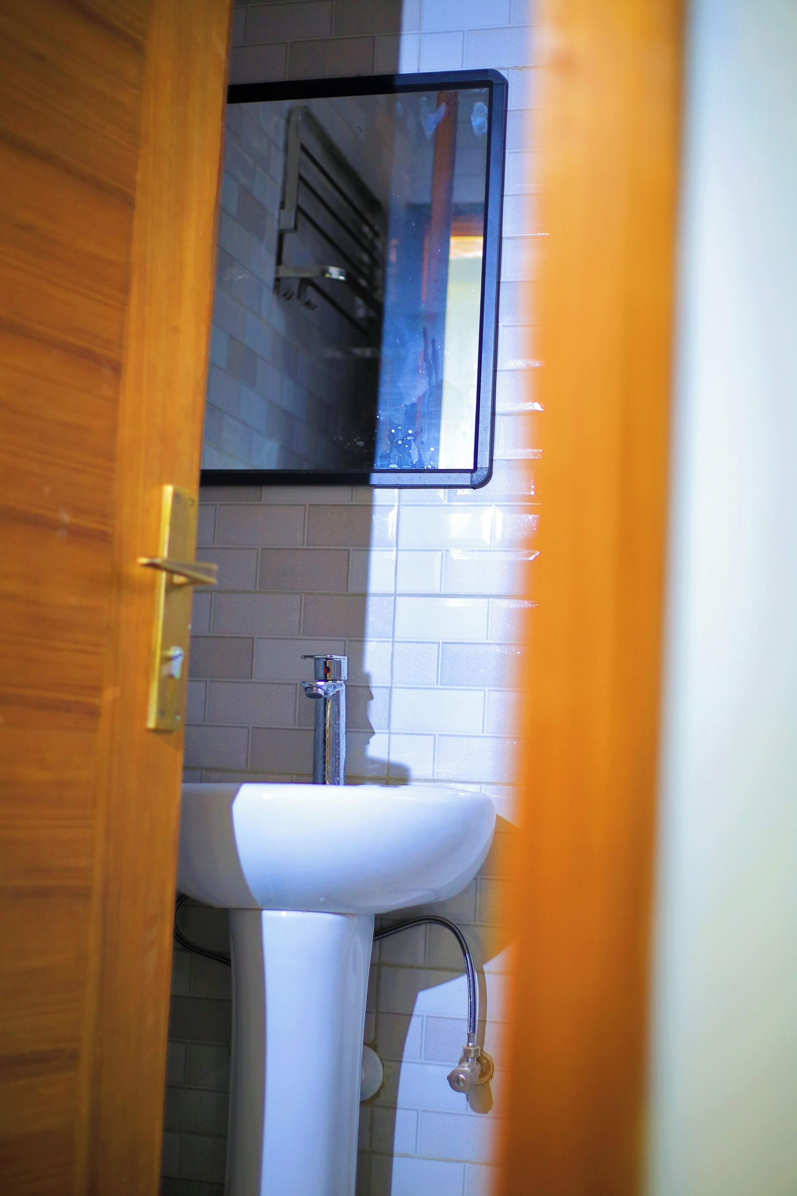 A bathroom with a white sink, a mirror, and a wooden door.