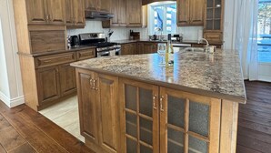 A kitchen with wooden cabinets, a granite countertop, and a built-in island with a sink.