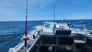 Un pont de bateau équipé de plusieurs cannes à pêche et d’un treuil, ce qui indique une activité de pêche.