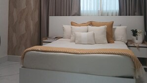 Une chambre à coucher moderne avec un grand lit, une table de chevet et une fenêtre avec des rideaux.