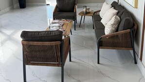 Un salon moderne avec un canapé, deux fauteuils, une table basse et une plante en pot.