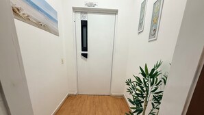 A hallway with a wooden floor, a door with a sign, and a potted plant.