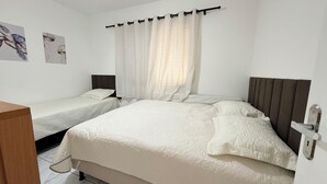 A double room with two single beds, a wooden desk, and a window with curtains.