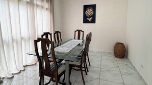A dining area with a glass table, wooden chairs, a vase, and a ceiling fan.