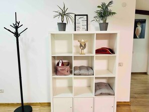 A white shelving unit with various items including a red bag, a decorative moose head, and two potted plants.