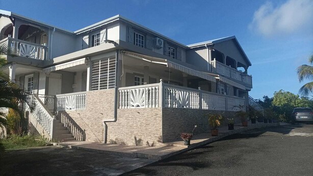 Una casa a due piani con un balcone, una scala e un vialetto.