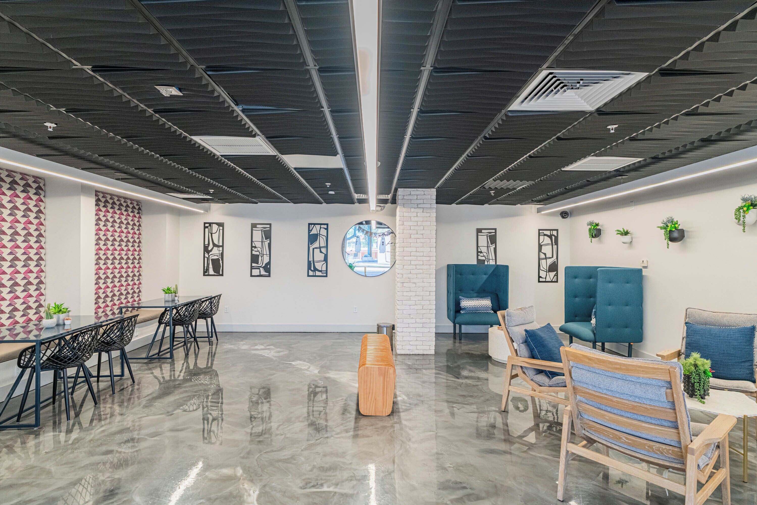 A modern office space with a polished floor, a central wooden bench, and seating areas with blue and wooden furniture.