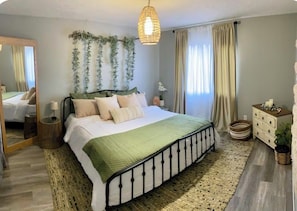 Ein Schlafzimmer mit Bett, Nachttisch, Kommode, Spiegel und einer Pendelleuchte.